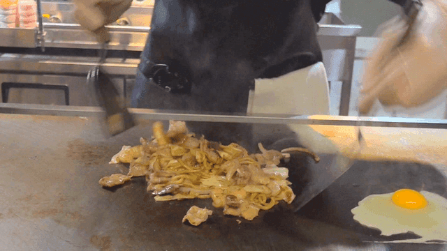 철판에서 야끼우동과 계란프라이를 요리하는 요리사