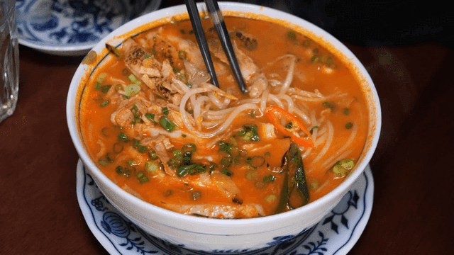 Chopsticks stirring spicy chicken rice noodles