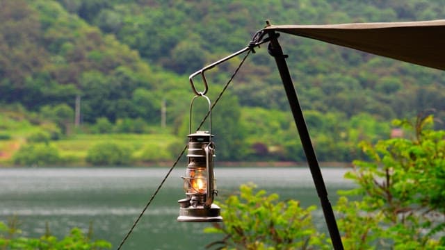 Lantern hanging from a tent near a serene lake