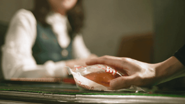 Hand giving cream bun to woman