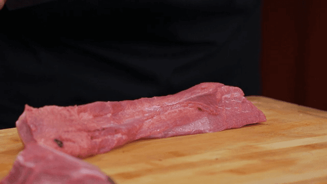 나무 도마 위에서 우설을 손질하는 사람