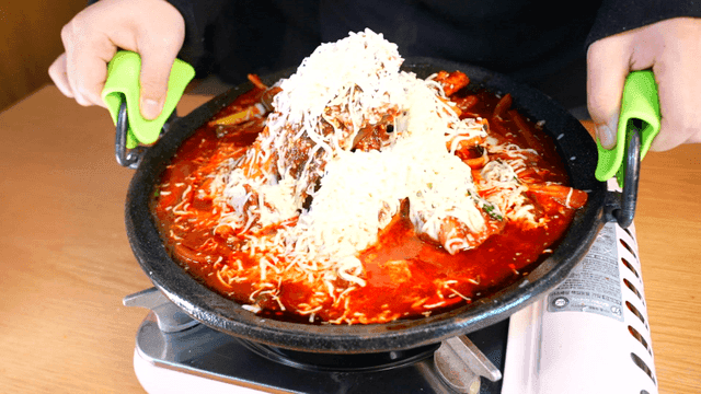 Spicy braised short ribs covered in cheese on gas burner