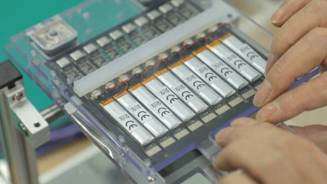 Engineer testing battery cells under blue lights in a lab
