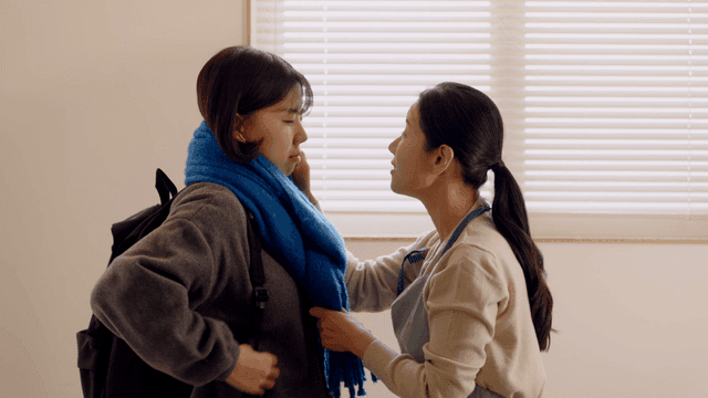 Mother tying scarf to her daughter as she goes out