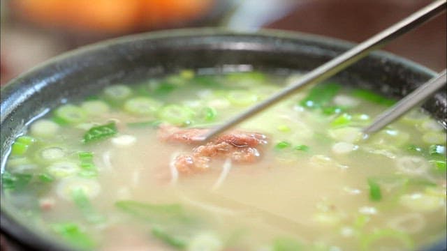 Picking up noodles and beef in the bowl with chopsticks