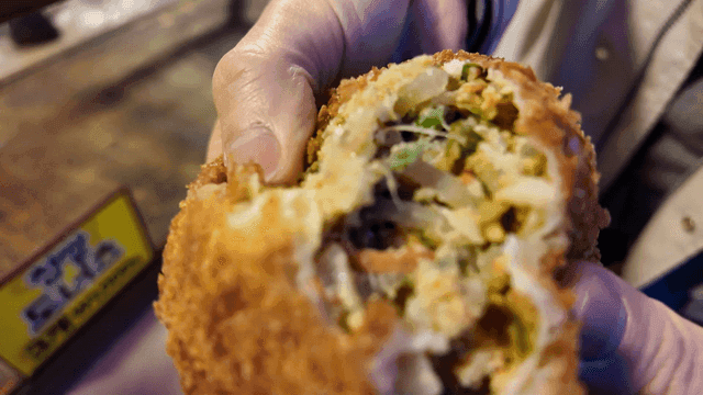 Tearing street croquette bread by person