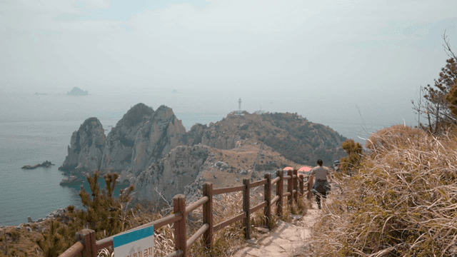 Hikers on a coastal trail with a lighthouse