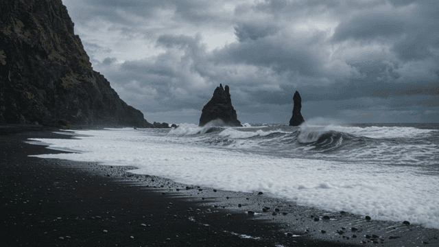 Black sandy rock beach where waves crash