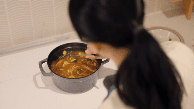 Back of woman stirring and cooking soybean paste stew