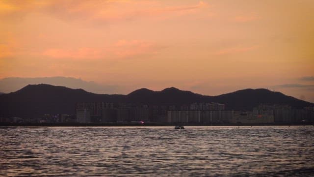 Sunset over a City Skyline by the Ocean and Mountains