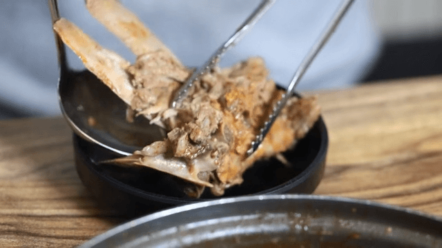Gamjatang meat lifted with tongs and ladle