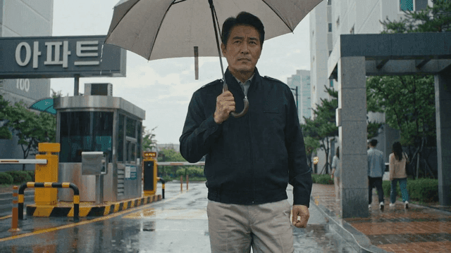 Security guard standing at apartment entrance holding umbrella