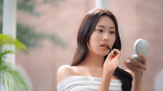 밝은 방에서 거울을 보며 립스틱을 바르는 여성