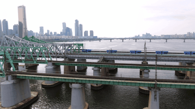 High-speed train crossing bridge in city landscape