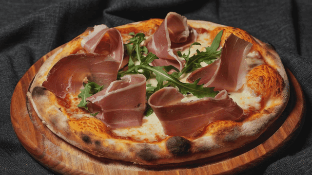 Pizza topped with prosciutto and arugula