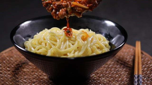 Pouring Spicy Stir-fry Sauce on Top of Noodles