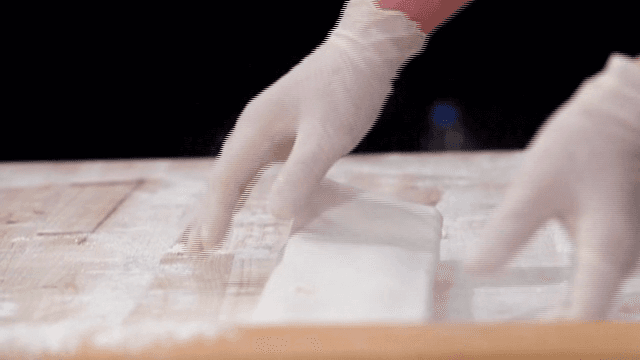 Hands preparing dough on a floured surface