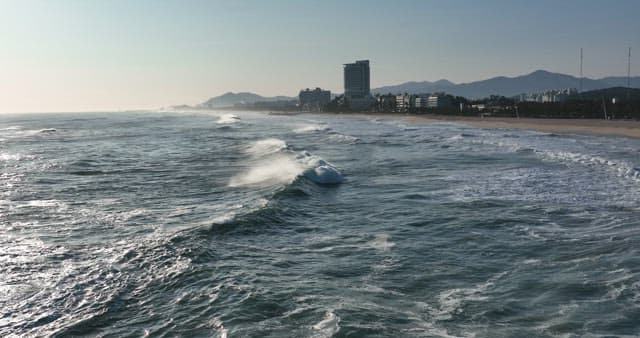 Serene Beachfront with Crashing Waves and Buildings