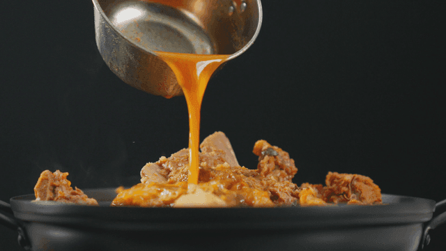 Pork backbone stew with broth being poured