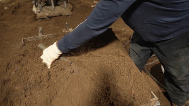 Worker shaping sand in a mold indoors