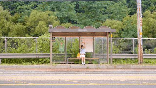 시골의 버스 정류장에서 기다리는 여성