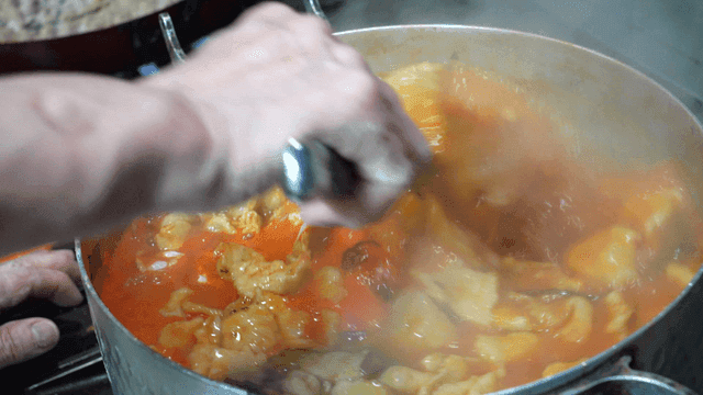 Chef stirring spicy dumplings boiling in pot