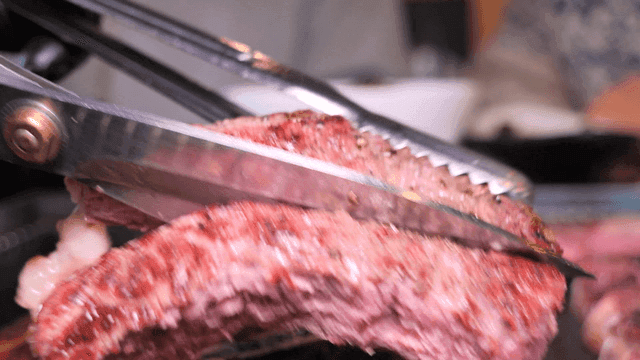 Cutting beef with tongs