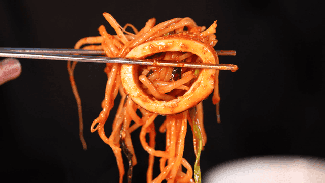 Spicy squid and bean sprout seafood stew picked up with chopsticks