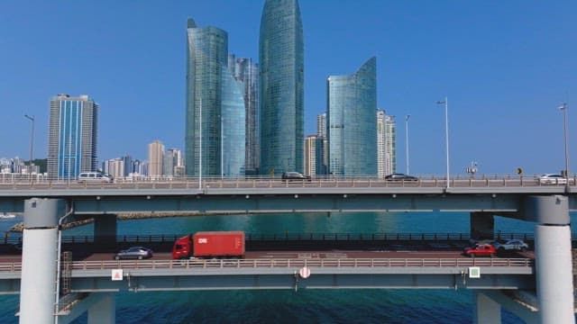 Cars traveling on a Gwangan Bridge with high-rise buildings in the background on a clear day