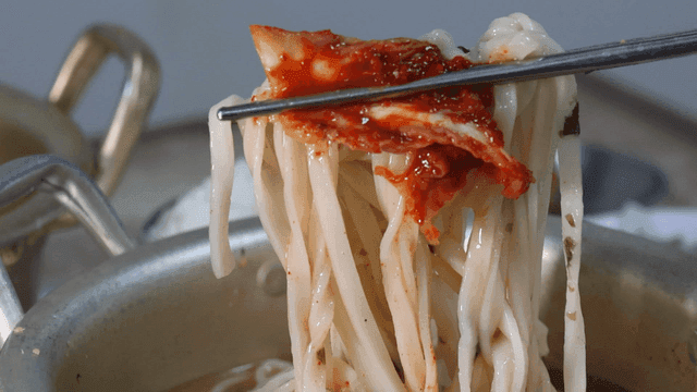 젓가락으로 집은 김치와 닭칼국수