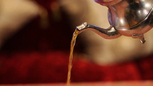 무늬가 있는 테이블 위에 민트티를 따르는 모습