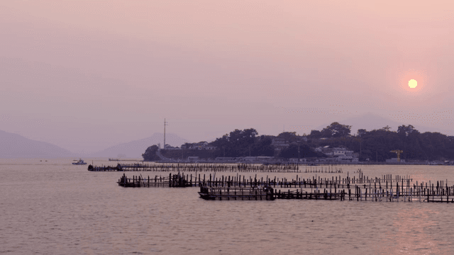 멀리 언덕이 보이는 고요한 바다의 일몰