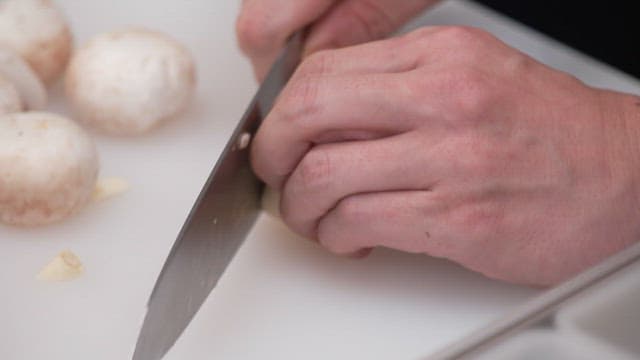 도마 위에서 칼로 마늘 편을 써는 모습