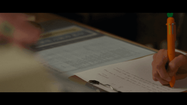 Person writing statement with carrot-shaped pen