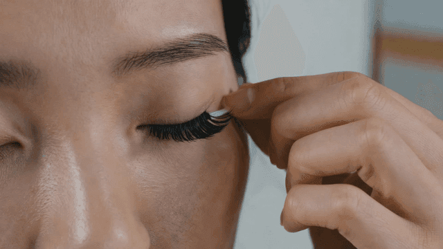 Woman applying artificial eyelashes with precision