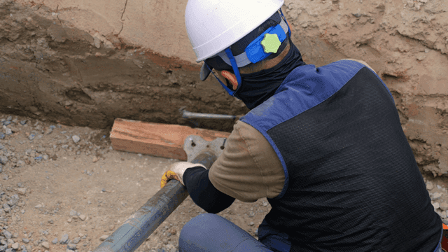 Worker securing pipes at a construction site