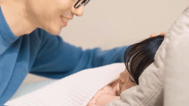 Father covering his sleeping child with a blanket