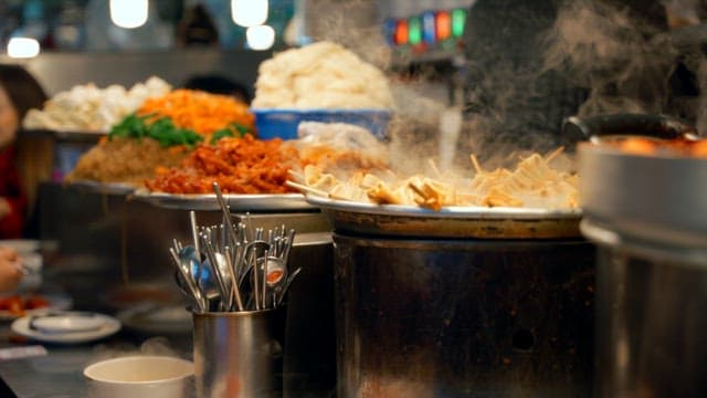 Busy Gwangjang Market street food stalls with steaming dishes