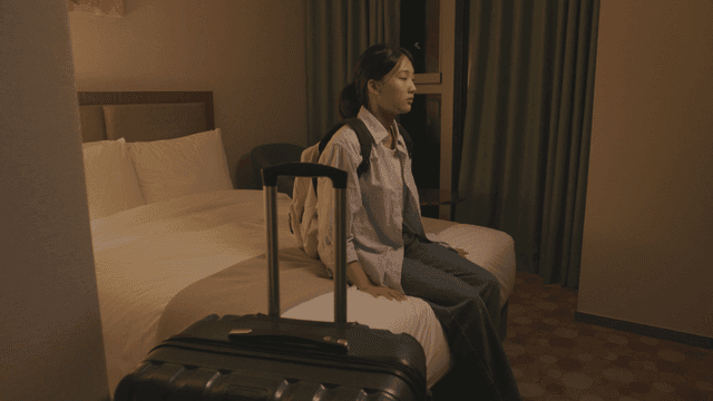 Woman arrives and sits down on a hotel bed