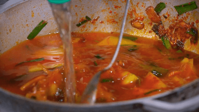 Adding water to stir-fried vegetables with seasoning