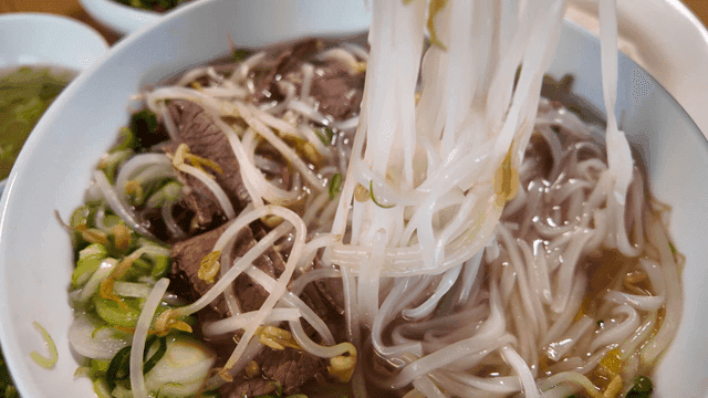 Chopsticks for scooping up rice noodles containing beef and bean sprouts