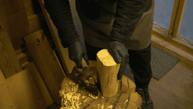 작업실에서 도끼로 나무를 다듬는 목수