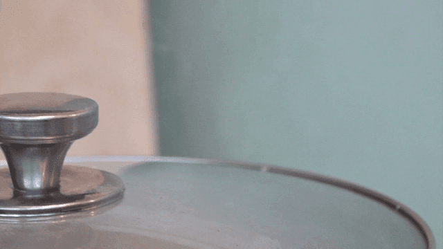 Gloved hand lifting steaming pot lid