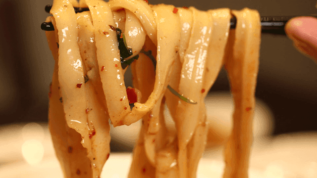 Chopsticks lifting spicy hand-cut noodles