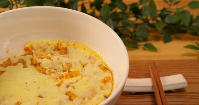 나무 숟가락으로 한 술 뜨는 치즈 그라탕