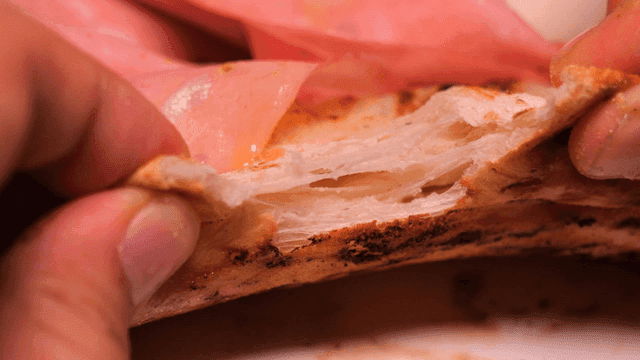 Hand tearing freshly baked oven-baked pizza