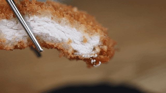 Pork cutlet served on black plate, dipped in salt
