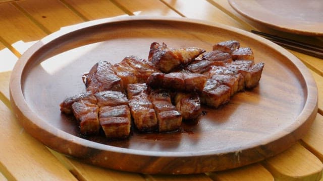 Marinated pork ribs and fresh green onions neatly plated on a wooden plate