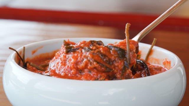 사발에 담긴 새콤달콤한 즙장을 숟가락으로 뜨는 모습