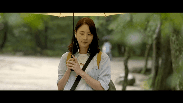 Woman walking with umbrella in forest